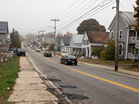 Cars travelling down repaired road on an overcast day.